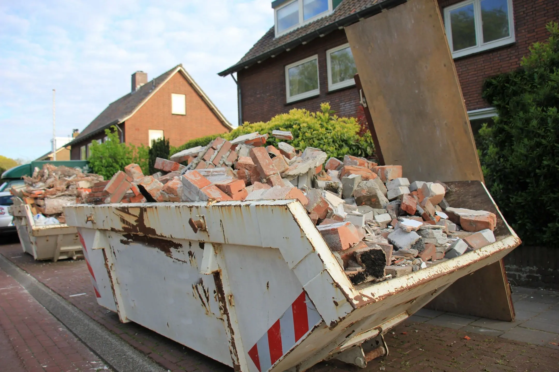 A dumpster full of rubble in front of a house.